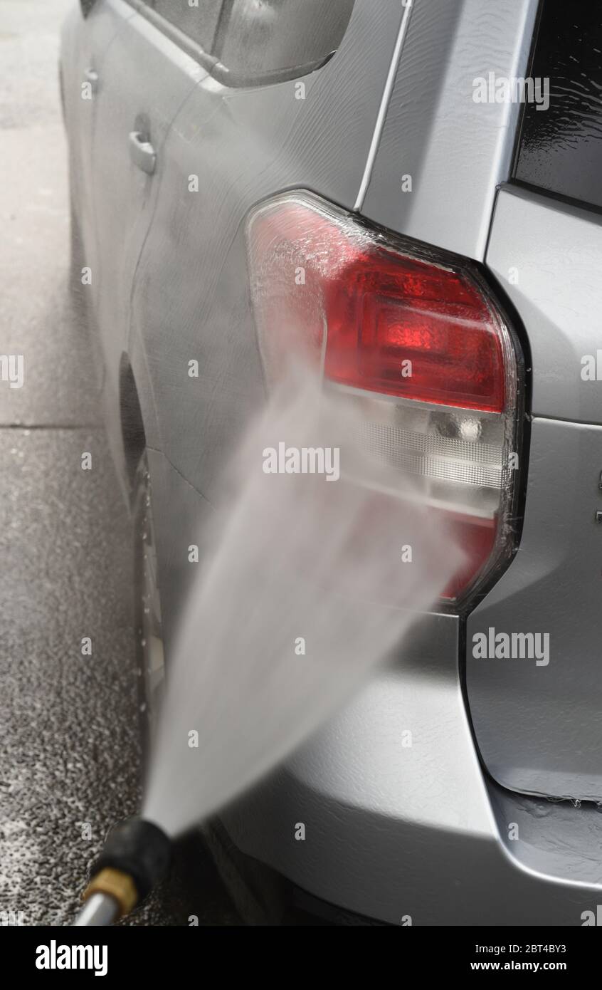 Sciacquare la luce posteriore su un'auto SUV color grigio argento 2016 Subaru Forester con una lancia a spruzzo a DIY (fai da te) autolavaggio Foto Stock