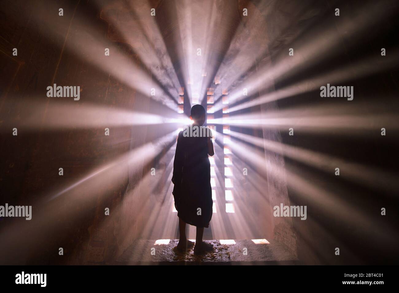 Vista posteriore silhouette di un monaco novizio in piedi vicino a una finestra, Mandalay, Myanmar Foto Stock