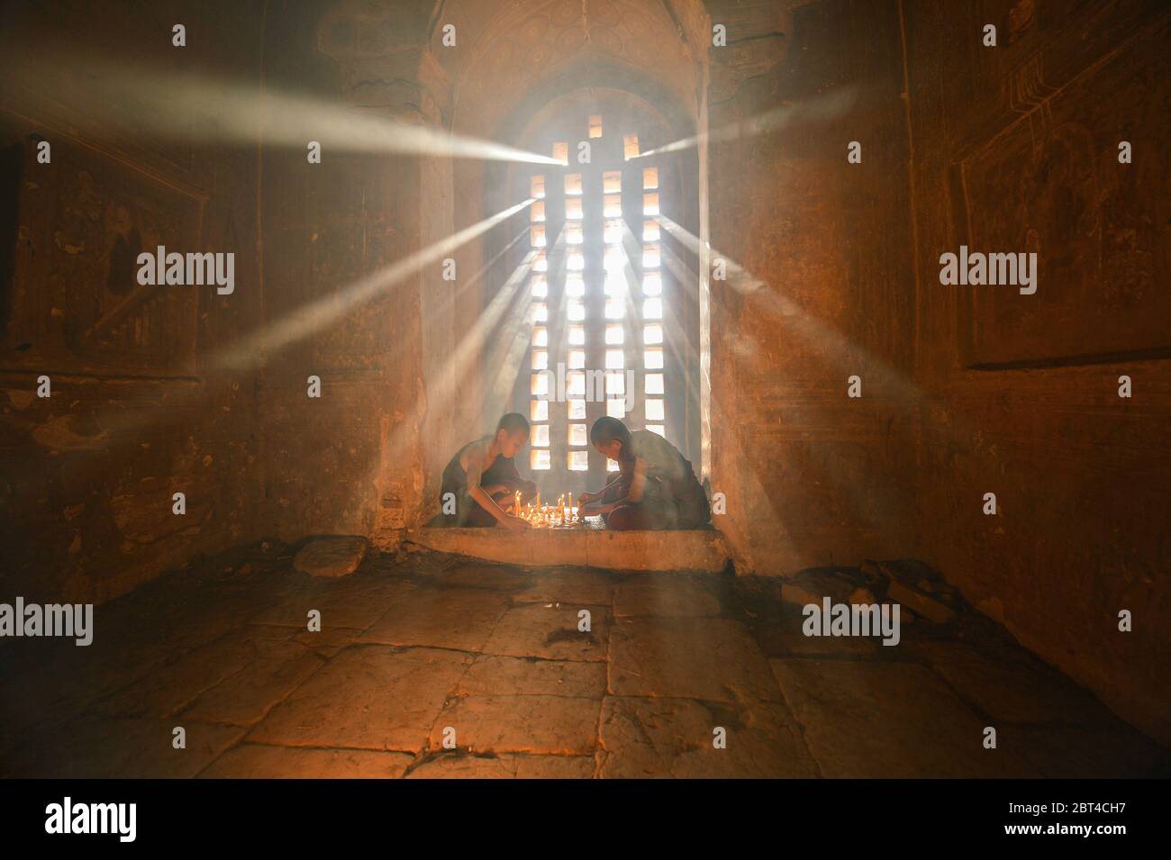 Due monaci novizi accendendo candele, Bagan, Mandalay, Myanmar Foto Stock