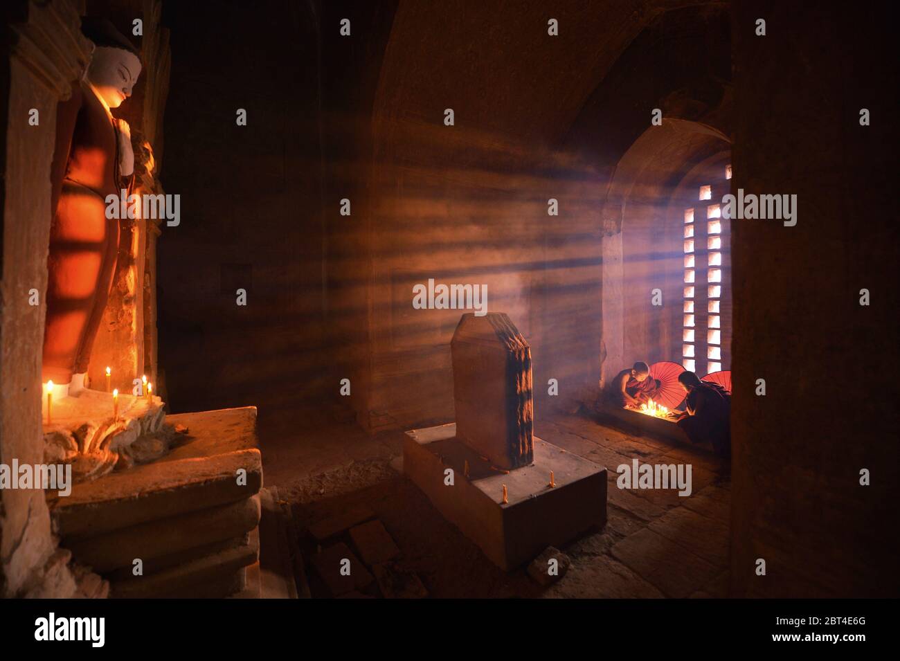 Due monaci novizi accendendo candele, Bagan, Mandalay, Myanmar Foto Stock