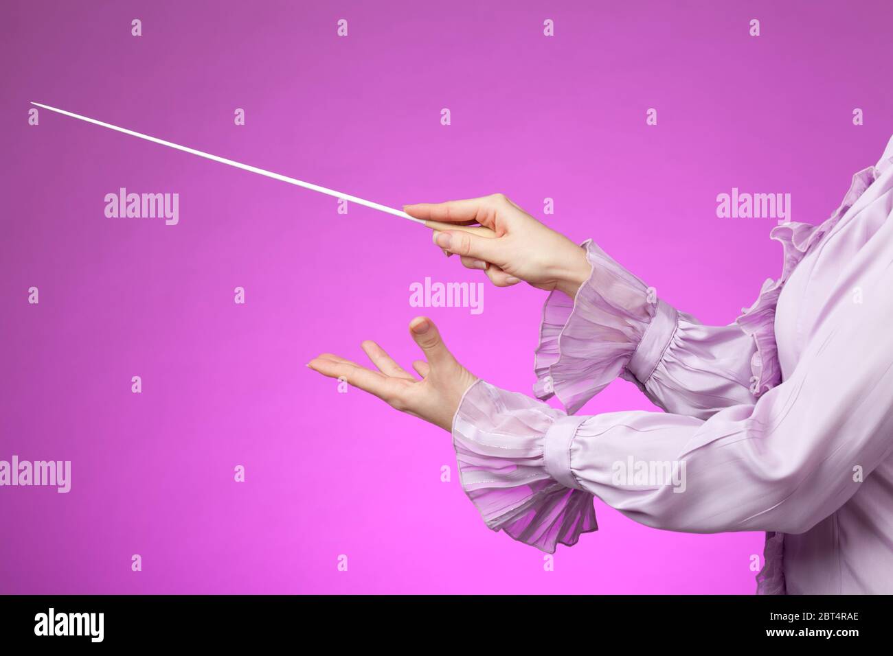 Femmina orchestra le mani, uno con il testimone. Sfondo rosa. Foto Stock