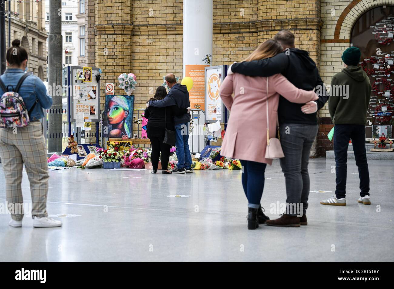 Le persone si convivono di fronte al monumento floreale alla stazione Victoria durante la commemorazione. Le persone si riuniscono alla stazione Victoria per celebrare il terzo anniversario dell'attacco terroristico alla Manchester Arena nonostante il blocco. Foto Stock