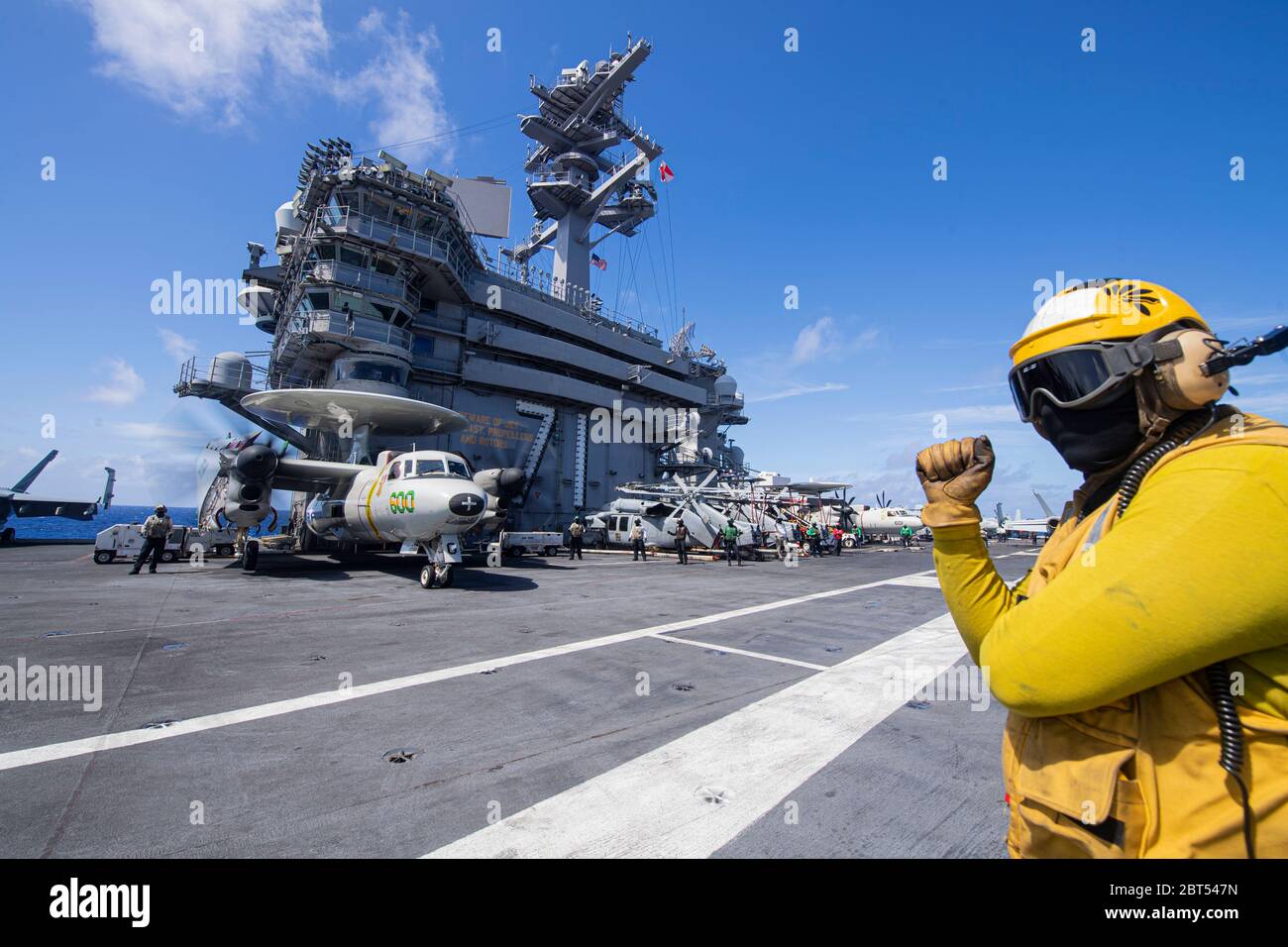 200522-N-TC338-1018 FILIPPINE MARE (22 maggio 2020) – U.S. Navy Aviation Boatswain's Mate (Aircraft Handling) 2a Classe Michael Scherer, da St. Paul, MINN., guarda le operazioni di volo sul ponte di volo della portaerei USS Theodore Roosevelt (CVN 71) 22 maggio 2020. Dopo una visita prolungata a Guam nel bel mezzo della pandemia globale COVID-19, Theodore Roosevelt sta svolgendo le qualifiche dei vettori durante un dispiegamento nell'Indo-Pacifico. (STATI UNITI Navy photo di Mass Communication Specialist 3° Classe Conner D. Blake) Foto Stock