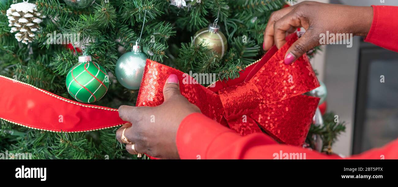 African Amerian Nigerian Woman decorare albero di Natale con decorazioni per natale - Banner Panorama Foto Stock