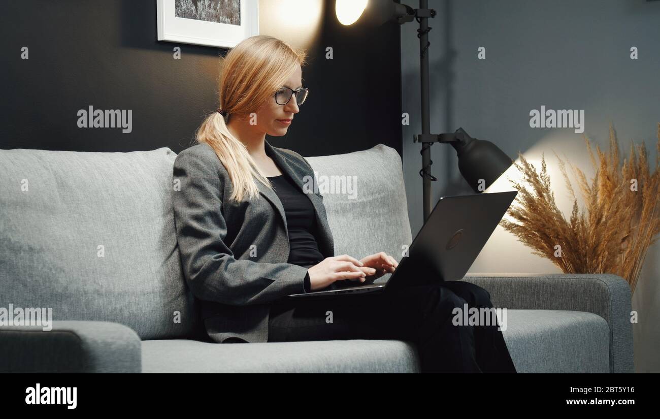 Donna d'affari che lavora con un computer portatile sul divano Foto Stock