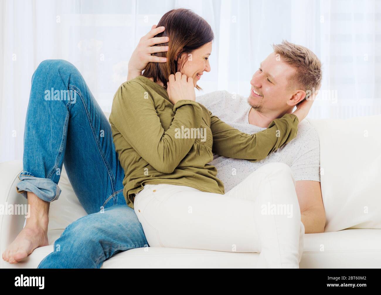 Le donne beatiful e suo marito stanno rilassandosi sul divano durante le feste Foto Stock