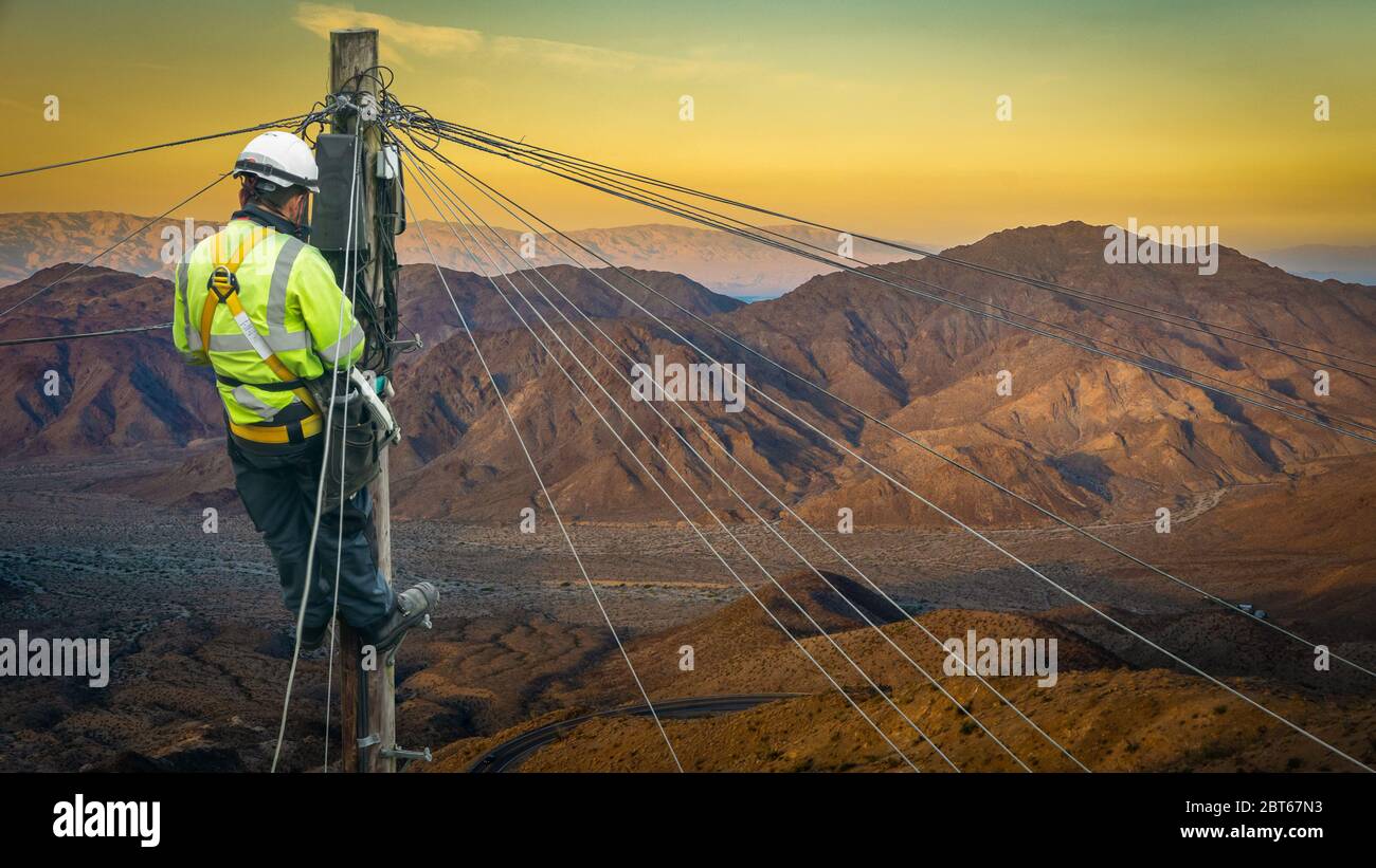 Lineman (o Lineworker o Engineer) in un paesaggio desertico remoto che fissa UNA linea telefonica Foto Stock