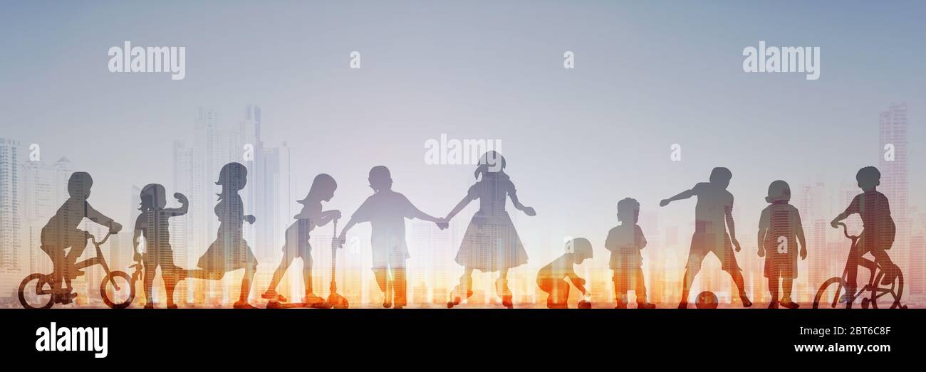 gruppo di bambini che giocano con il cielo del tramonto e lo skyline della città sullo sfondo; profilo della gente Foto Stock