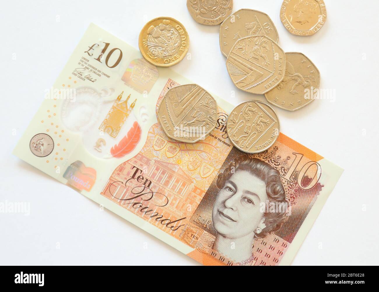 Dieci 10 sterline britanniche e monete su sfondo bianco Foto Stock