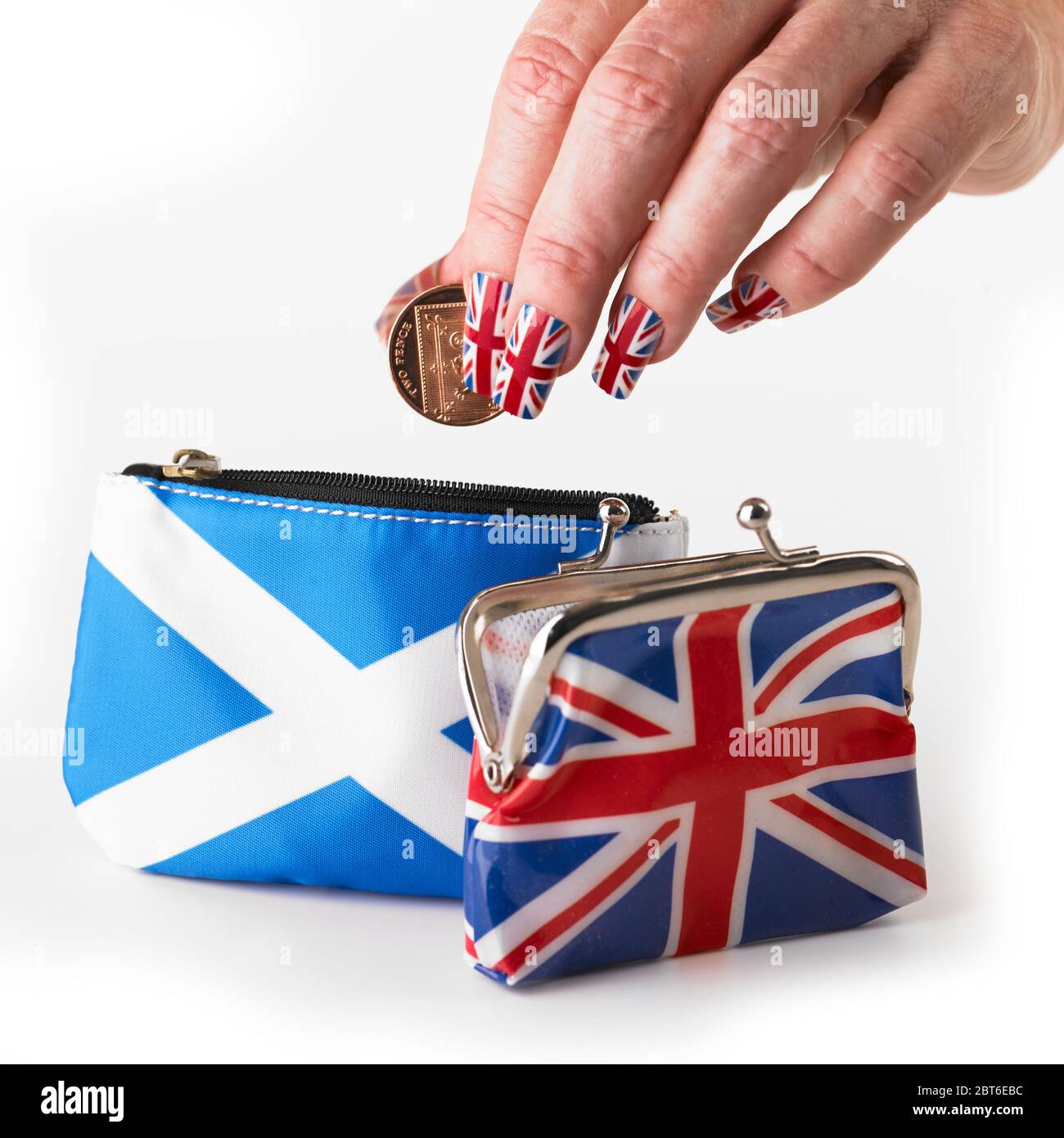 Mano che indossa bandiera dell'Unione falsi chiodi che mettono le monete del Regno Unito in borsa scozzese del styre con la borsa di Union Jack davanti Foto Stock