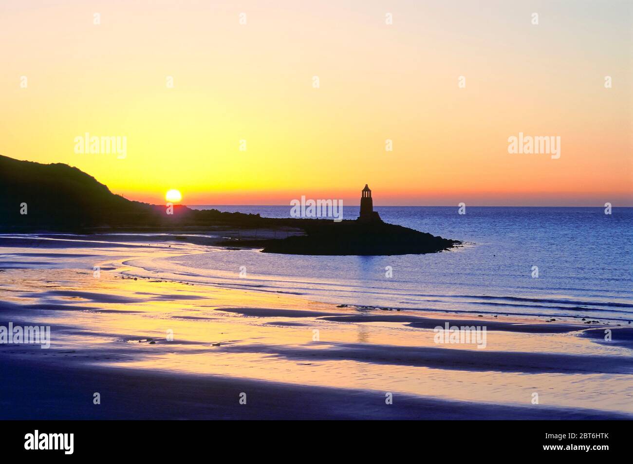 Port logan Bay al tramonto con il vecchio faro, Rhinns di Galloway Foto Stock