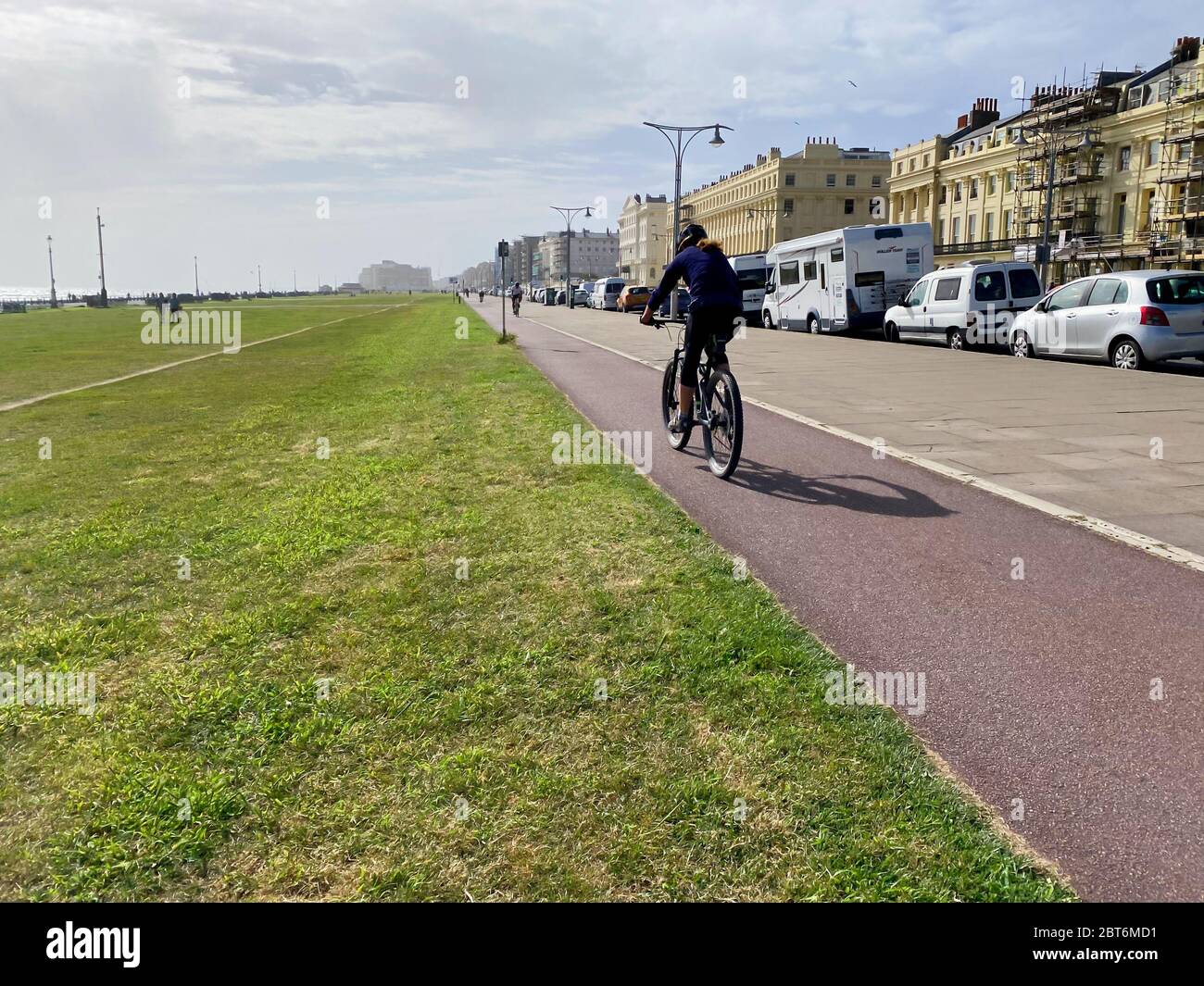 Persona che cavalcano lungo una pista ciclabile in città Foto Stock