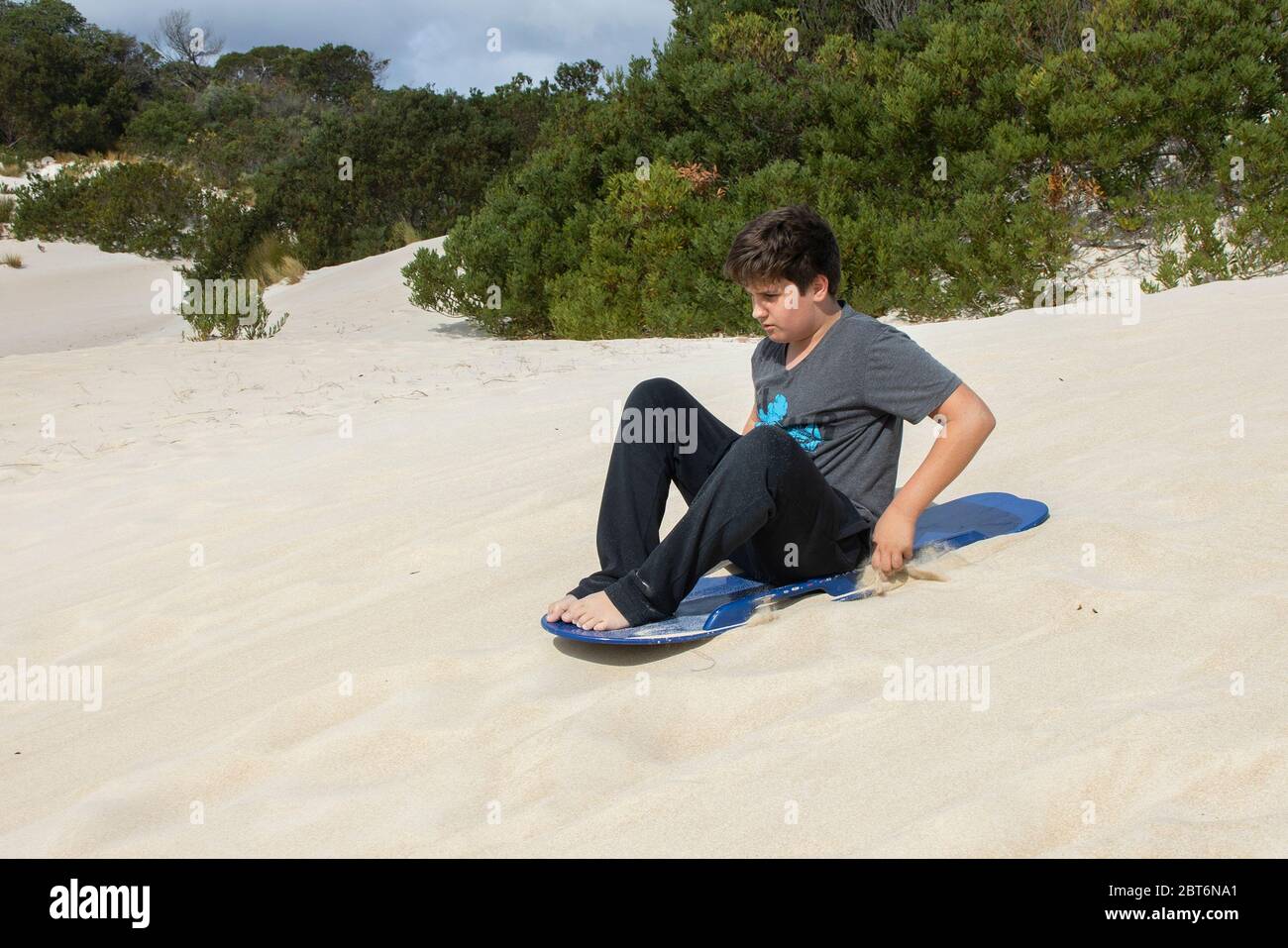 Kangaroo Island, Australia - 9 Marzo 2020: Un adolescente surf sulla sabbia a Kangaroo Island, Australia. Foto Stock