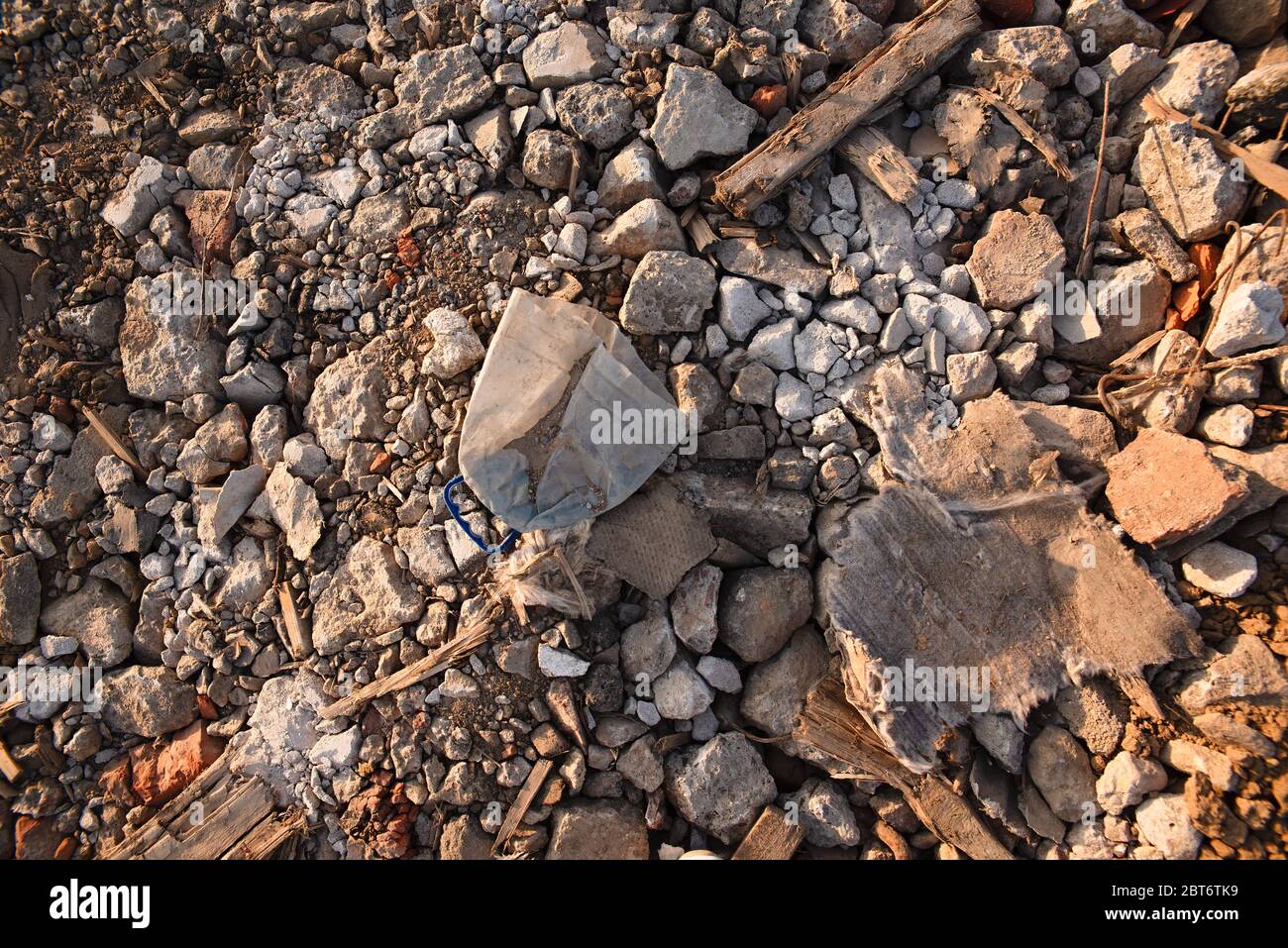 ghiaccio di plastica spazzatura sulle pietre, una vecchia bottiglia gettata da lumi, pietre e rifiuti, inquinamento ambientale, un pezzo di stoffa come rifiuti si trova su Foto Stock