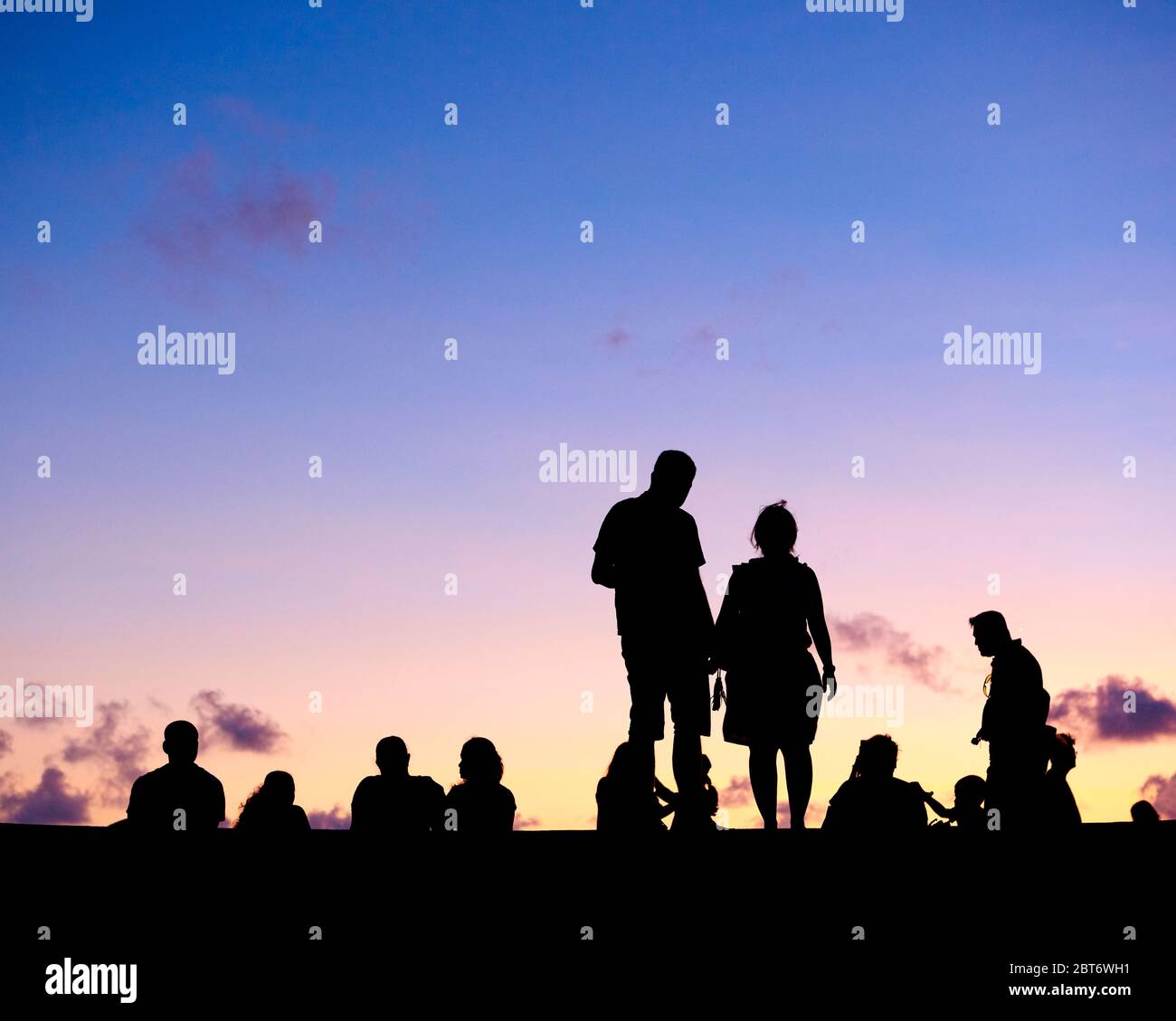 Silhouette di persone irriconoscibili contro il cielo crepuscolo. Foto Stock