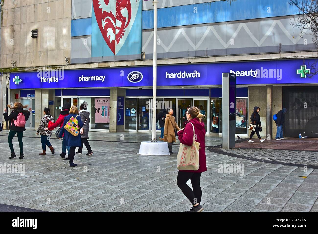 Gli amanti dello shopping passino davanti al negozio principale Boots nella Queen Street di Cardiff. Foto Stock