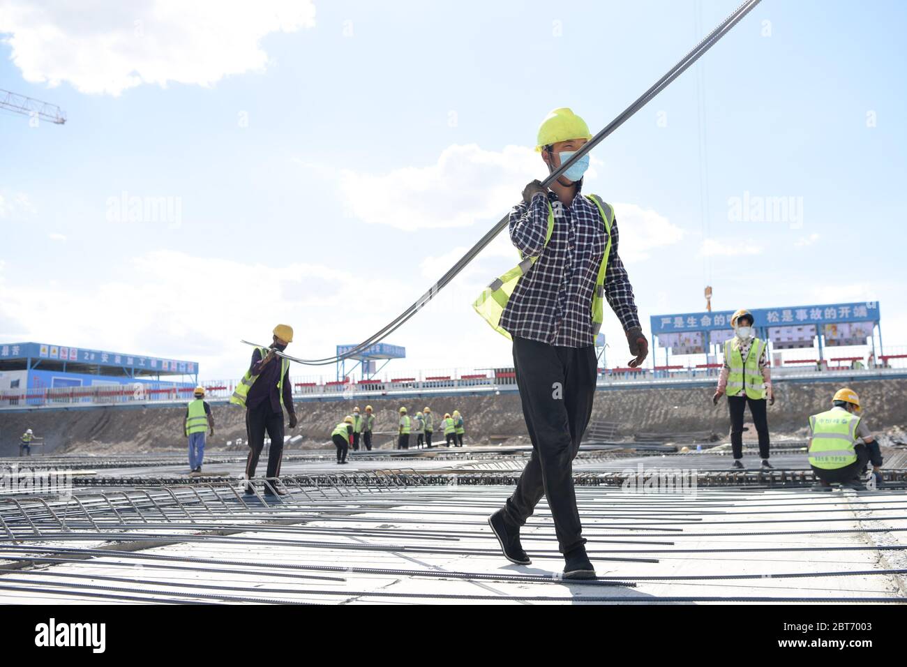 Urumqi, la regione autonoma cinese di Xinjiang Uygur. 23 maggio 2020. I lavoratori spostano le barre di rinforzo nel cantiere per il progetto di espansione dell'aeroporto internazionale di Urumqi Diwopu a Urumqi, regione autonoma Xinjiang Uygur, nella Cina nord-occidentale, 23 maggio 2020. Il progetto comprende un nuovo terminal di 500,000 metri quadrati, due piste di oltre 3,000 metri, un centro di trasporto integrato fino a 92,700 metri quadrati, un parcheggio di oltre 250,000 metri quadri e attrezzature ausiliarie. Il progetto dovrebbe essere completato entro il 2023. Credit: Ding Lei/Xinhua/Alamy Live News Foto Stock