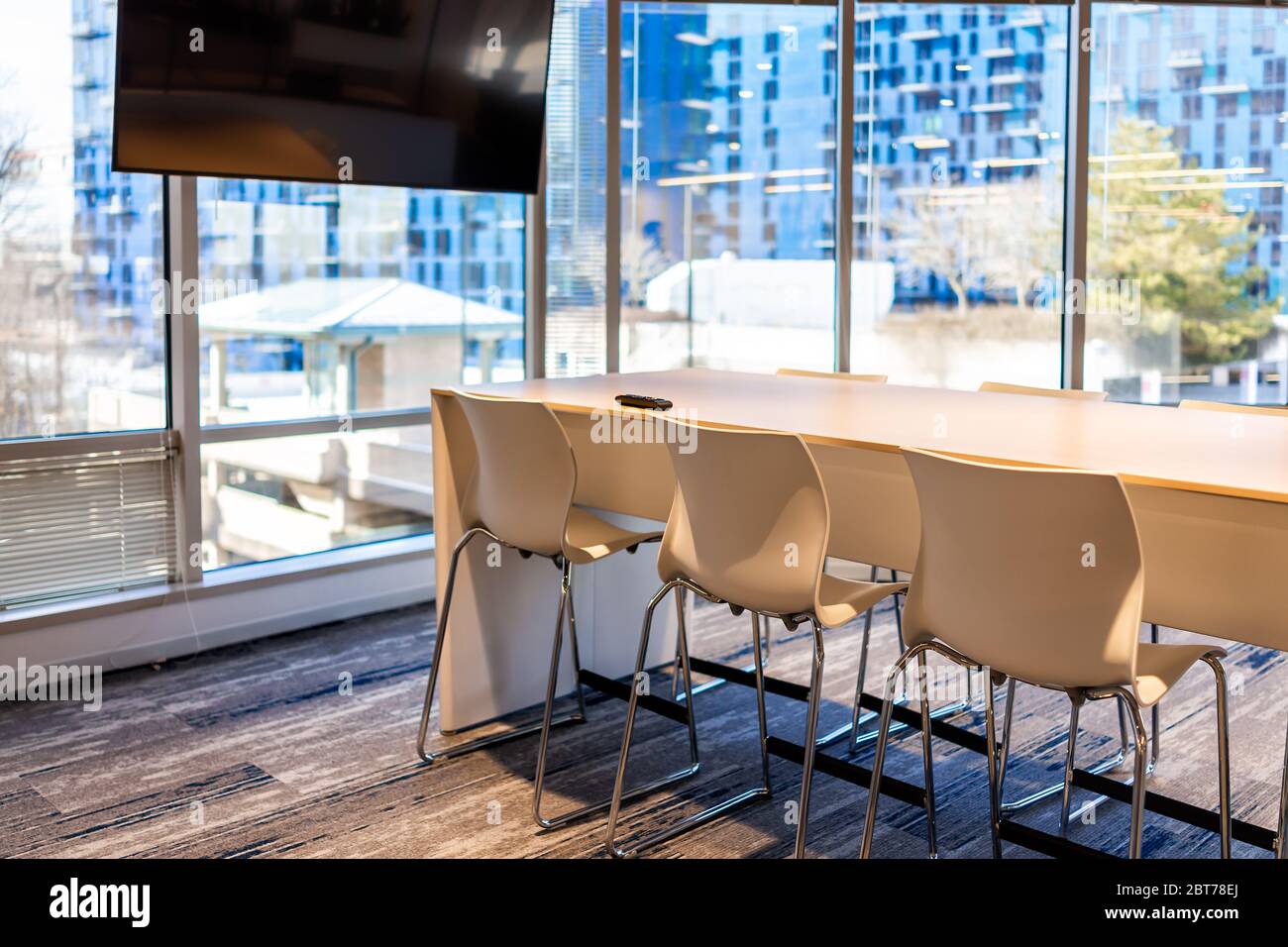 Moderno edificio per uffici con contemporaneo tavolo da lavoro aziendale in legno con televisore e sedie vuoto nessuno Foto Stock