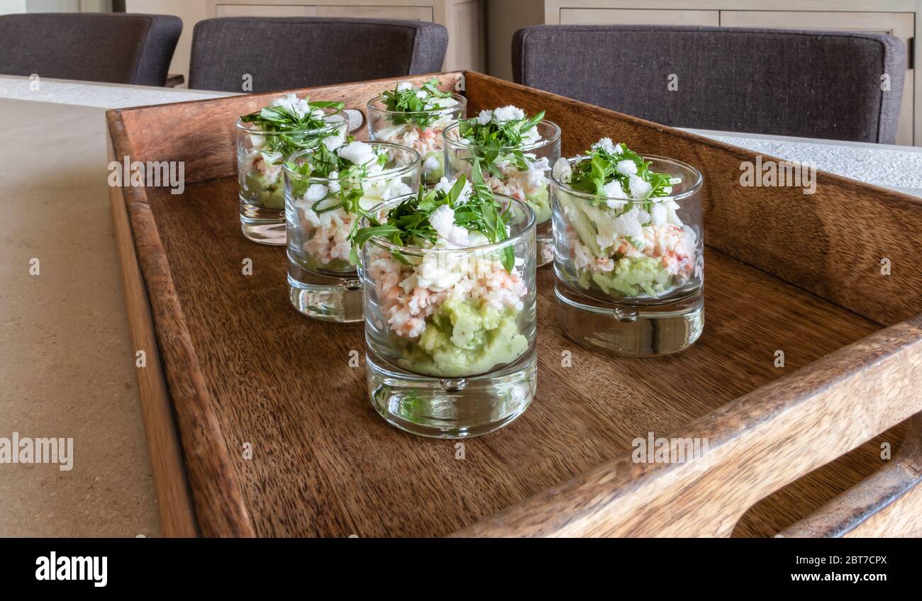 Bicchieri da aperitivo natalizio con mousse di avocado e granchio del Mare del Nord su un vassoio di legno Foto Stock
