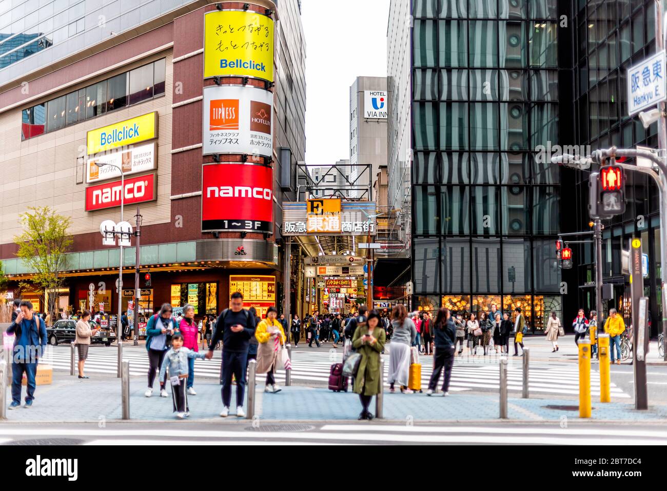 Osaka, Giappone - 13 aprile 2019: Edifici moderni vicino alla stazione con il traffico di persone che attraversano la strada per la famosa galleria e cartelli commerciali Foto Stock