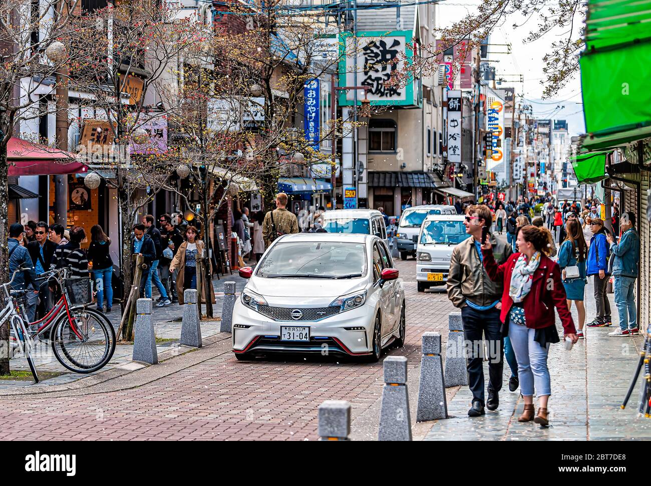 Nara, Giappone - 14 aprile 2019: Turisti persone a piedi sul marciapiede strada Sanjo dori nel centro città verso il parco con negozi e ciliegia bl Foto Stock