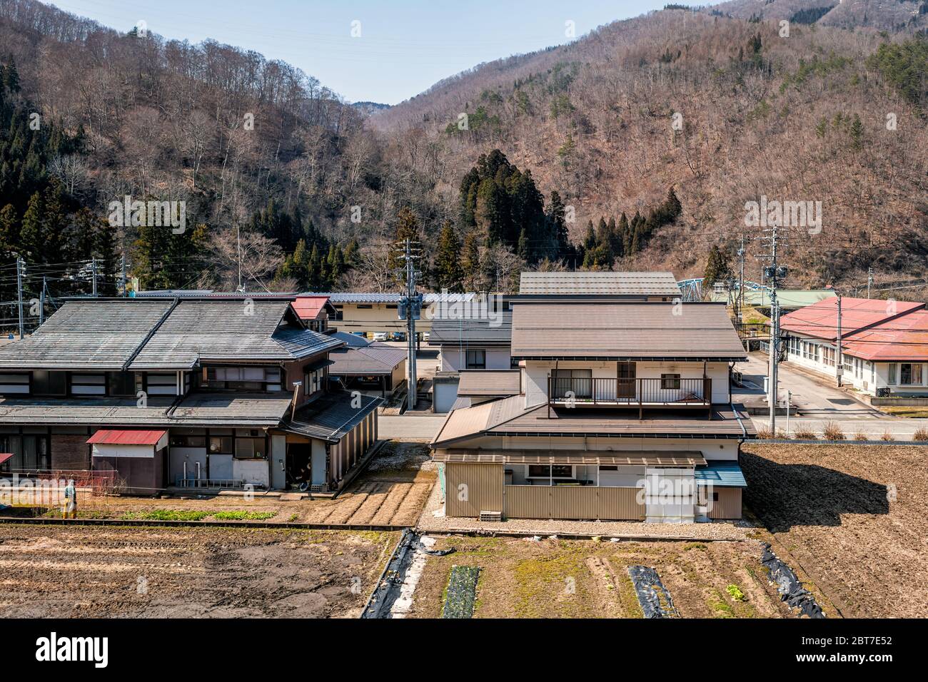 Hida, Giappone - 6 aprile 2019: Campagna con vista su terreni coltivati a riso nella zona rurale nella prefettura di Gifu con campo marrone in montagne alpi e tradizione Foto Stock