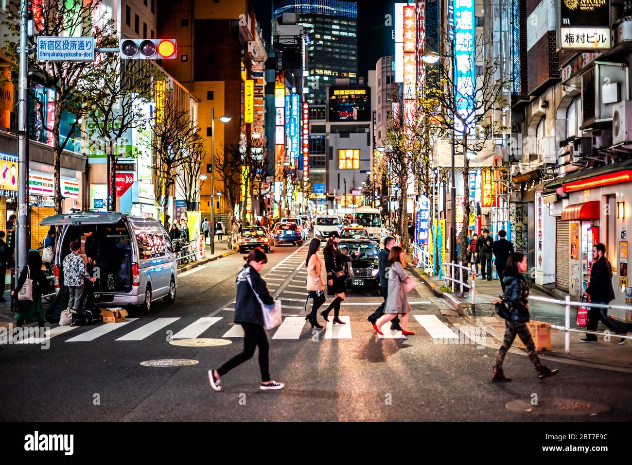 Tokyo, Giappone - 3 aprile 2019: Persone che attraversano strada in centro città con luci notturne al neon paesaggio urbano su kuyakusho-dori con segno vicino kabukicho Foto Stock