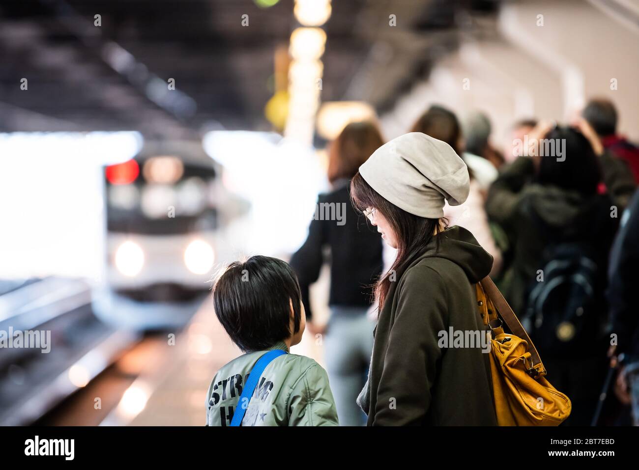 Utsunomiya, Giappone - 5 aprile 2019: Linea ferroviaria locale della piattaforma della stazione JR per Nikko con la madre e la bambina della gente locale in attesa e in arrivo headligh Foto Stock