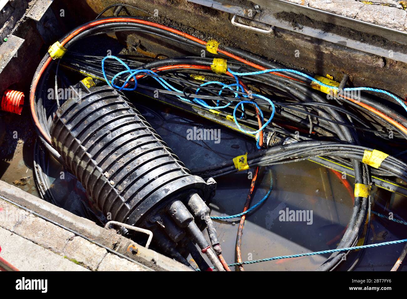 Guardando nel buco della telecomunicazioni in pavimentazione con il cablaggio tradizionale in rame, come nuovo cavo in fibra ottica è passante, Regno Unito Foto Stock