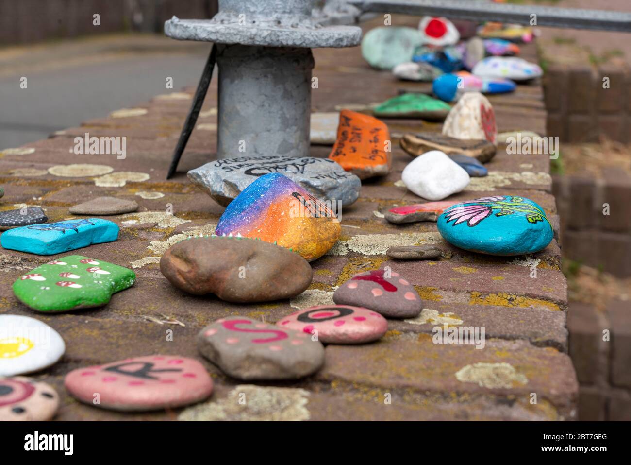 Pietre dipinte su un muro a Duisburg-Orsoy, le cosiddette pietre di Corona, serpenti di pietra, che per la maggior parte i bambini dipingono e si uniscono a una fila, azione di nuovo Foto Stock