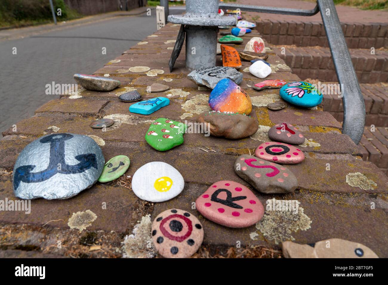 Bemalte Steine auf einer Mauer a Duisburg-Orsoy, s.g. Kinder, Steinschlangen, die meist Kinder bemalen und zu einer Reihe zusammen legen, Akti Foto Stock