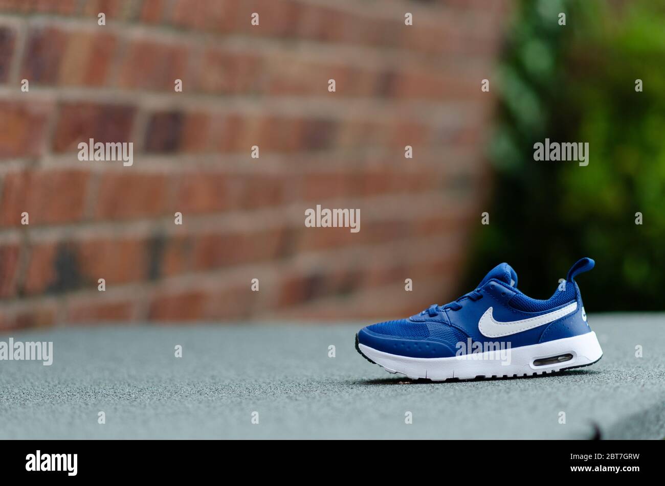 La foto ravvicinata del paio di scarpe Nike Air blu per bambini. Il muro di mattoni è sullo sfondo. Per l'imaging è stato utilizzato un campo visivo poco profondo. Foto Stock