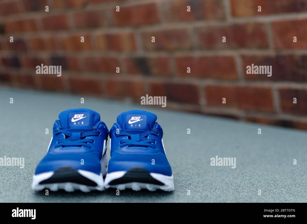 La foto ravvicinata del paio di scarpe Nike Air blu per bambini. Il muro di mattoni è sullo sfondo. Per l'imaging è stato utilizzato un campo visivo poco profondo. Foto Stock