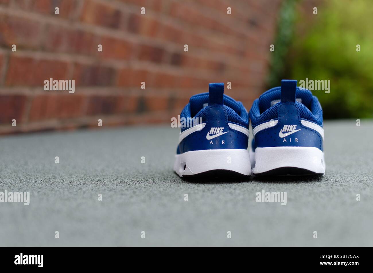 La foto ravvicinata dell'paio di scarpe Nike Air blu per bambini sull'erba verde vibrante. Per l'imaging è stato utilizzato un campo visivo poco profondo. Foto Stock