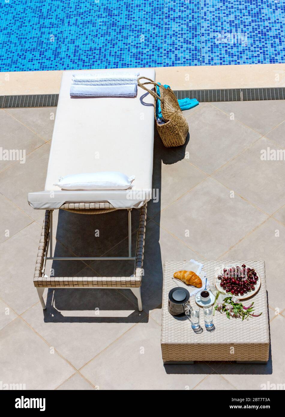 lettino, tavolo con frutta, caffè e croissant vicino alla piscina esterna, vista dall'alto Foto Stock