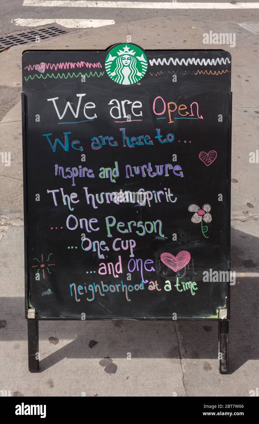 Il cartello del marciapiede davanti a uno Starbucks dice che è aperto e con citazioni e doodles ispiratori durante il coronavirus o la pandemia del covid-19 Foto Stock