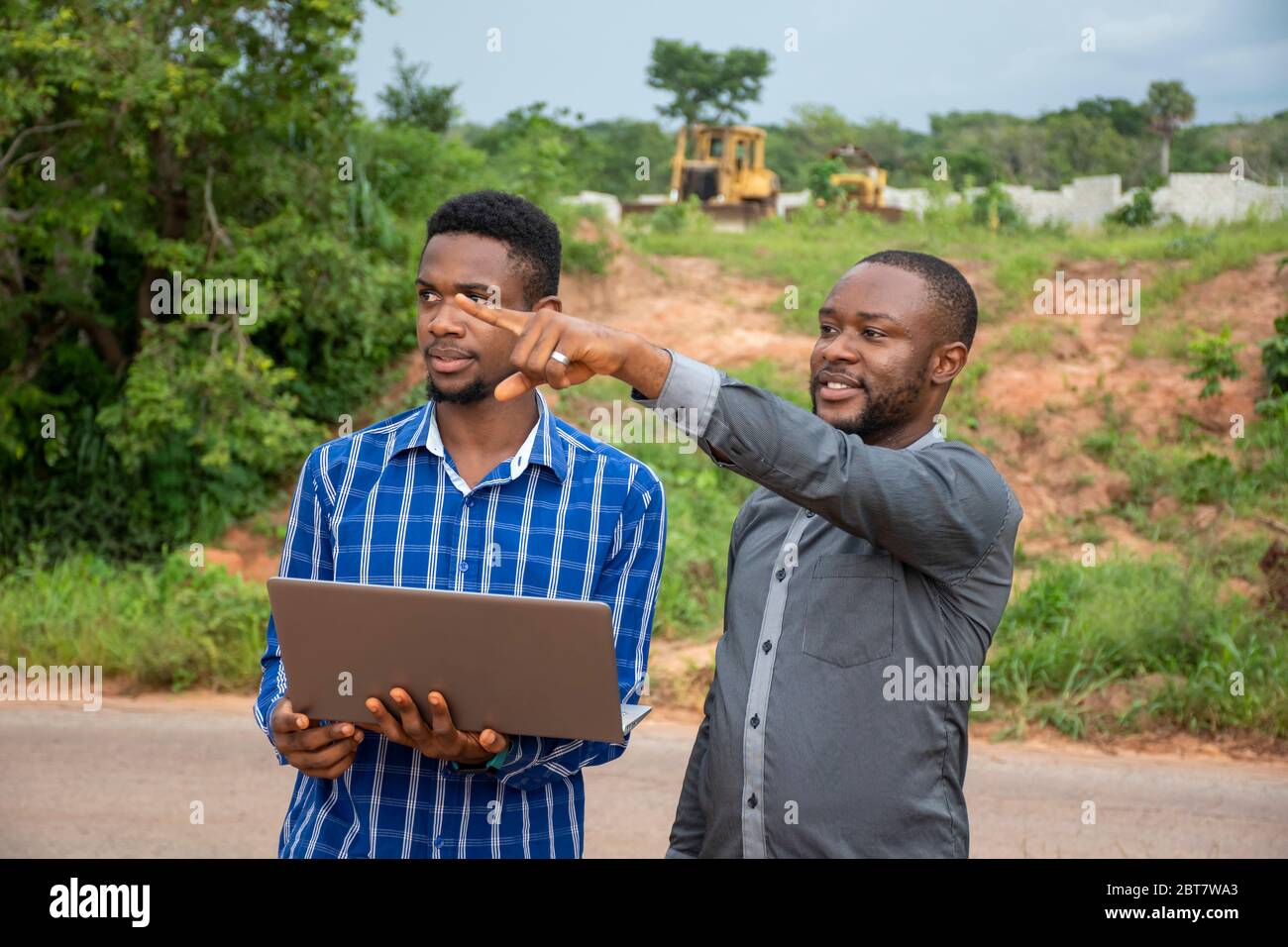 uomini d'affari africani, che discutono e si interrogano su un terreno, utilizzando un computer portatile Foto Stock