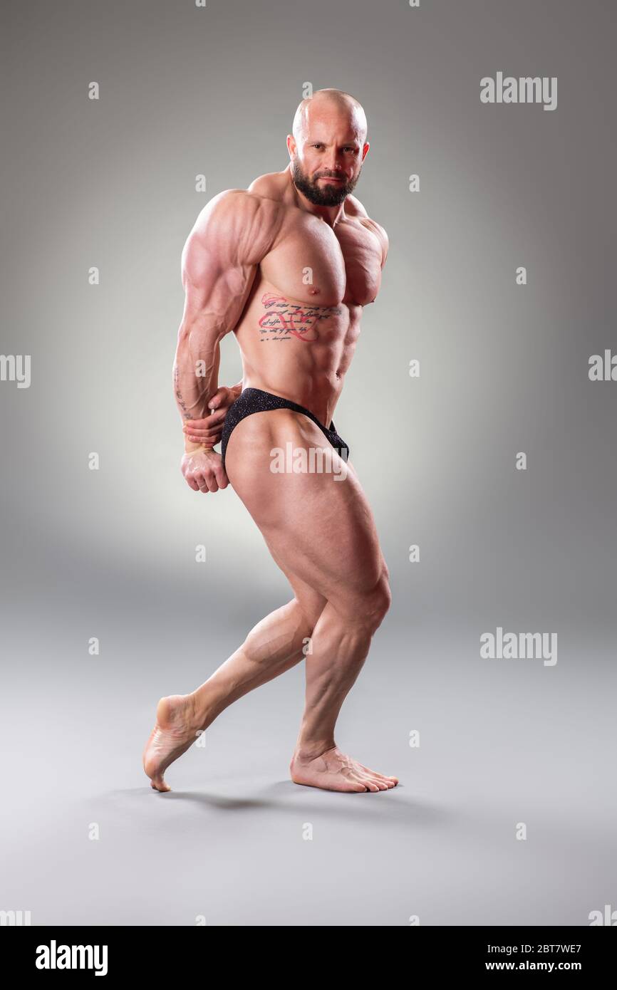 Bodybuider muscolare sexy in posa su sfondo grigio Foto Stock