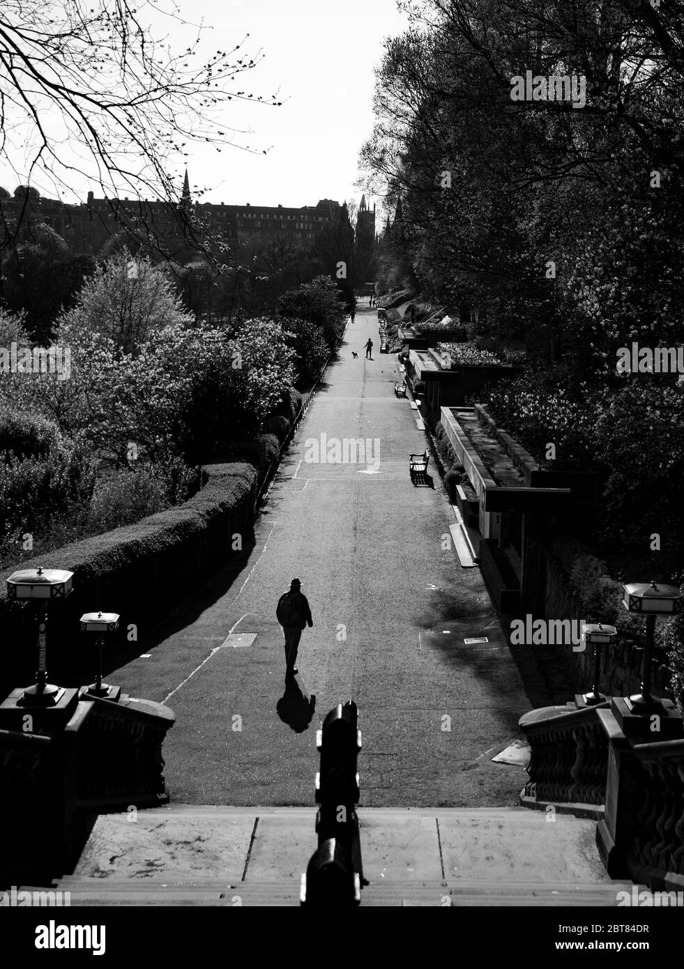Uomo solitario che cammina verso la scalinata fuori da un deserto Princes Street Gardens Edimburgo durante il blocco 2020. Scatti in bianco e nero di grande effetto. Foto Stock