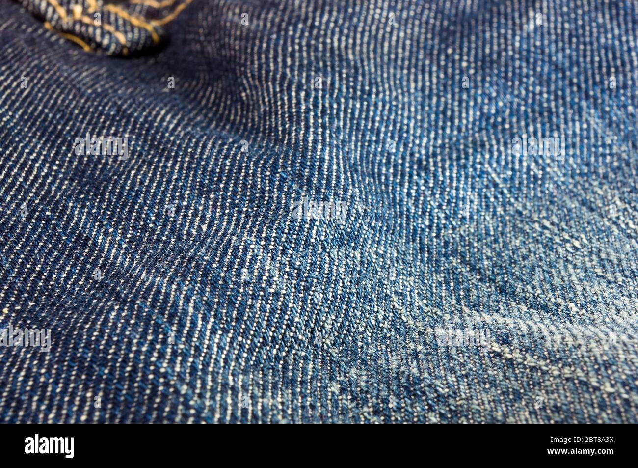 Articoli di abbigliamento stonewashed blue jeans scoloriti tessuto di cotone texture con cuciture, fibbie, bottoni e rivetti, macro close-up Foto Stock