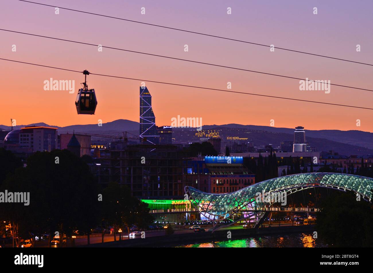 Tbilisi: Tramonto sul Ponte della Pace, con una funivia che attraversa il fiume Kura (Repubblica di Georgia) Foto Stock