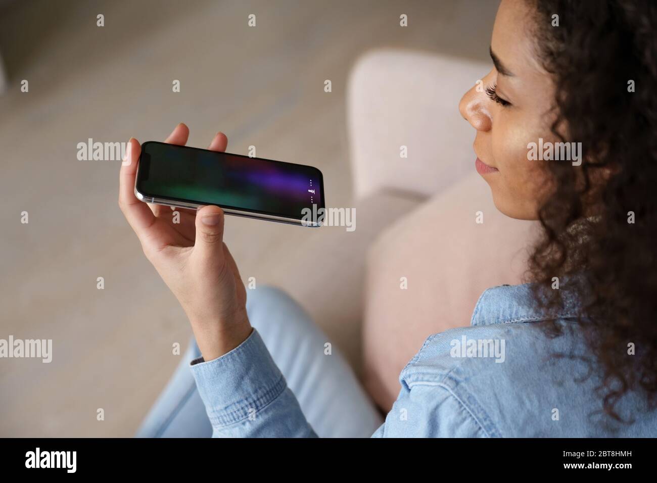 Donna africana che tiene il telefono cellulare utilizzando l'assistente di riconoscimento vocale. Foto Stock