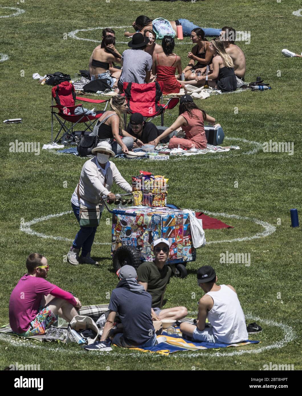 San Francisco, Stati Uniti. 24 maggio 2020. Un venditore di snack mascherato spinge il suo carrello attraverso i gruppi in circoli pre-disegnati nel Parco Delores a San Francisco sabato 23 maggio 2020. Il clima caldo e un fine settimana di vacanza hanno portato fuori migliaia per esercitarsi i loro propri marchi di distanza sociale. Photo by Terry Schmitt/UPI Credit: UPI/Alamy Live News Foto Stock