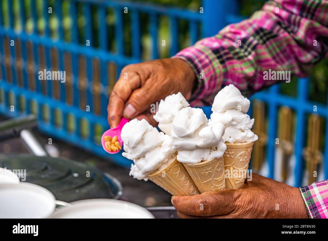L'uomo mette il gelato bianco in tazze Foto Stock