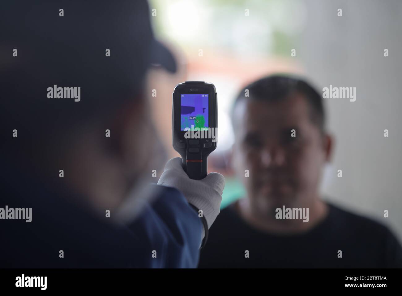 Bucarest, Romania - 7 maggio 2020: Dettagli con un negozio guardia di sicurezza clienti termoscansione prima di entrare nel negozio durante l'epidemia covid-19. Foto Stock