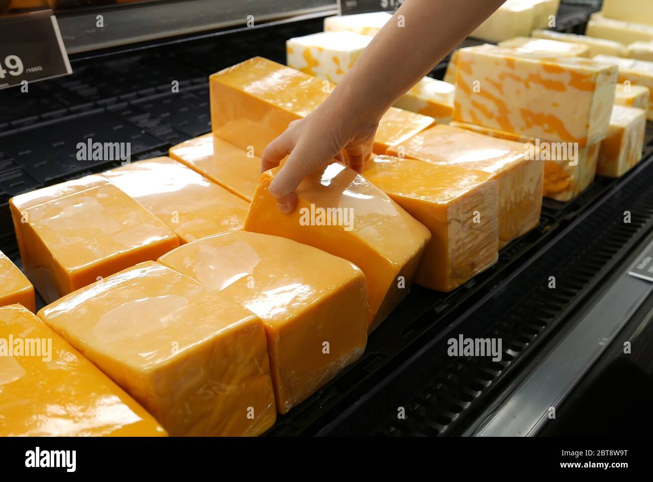 Movimento della mano della donna che raccoglie il formaggio all'interno del negozio Foto Stock
