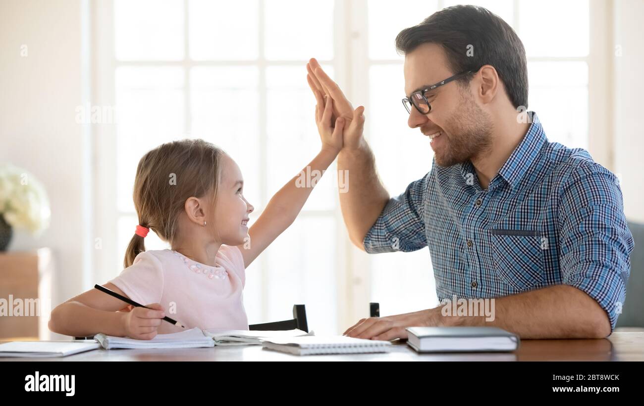 Papà felice e piccola figlia celebrare il successo di studiare insieme Foto Stock