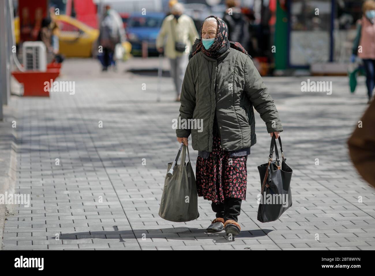 Bucarest, Romania - 16 aprile 2020: Gli anziani che indossano maschere protettive fanno il loro shopping in un mercato aperto occupato a Bucarest durante l'epidemia di covid-19 Foto Stock