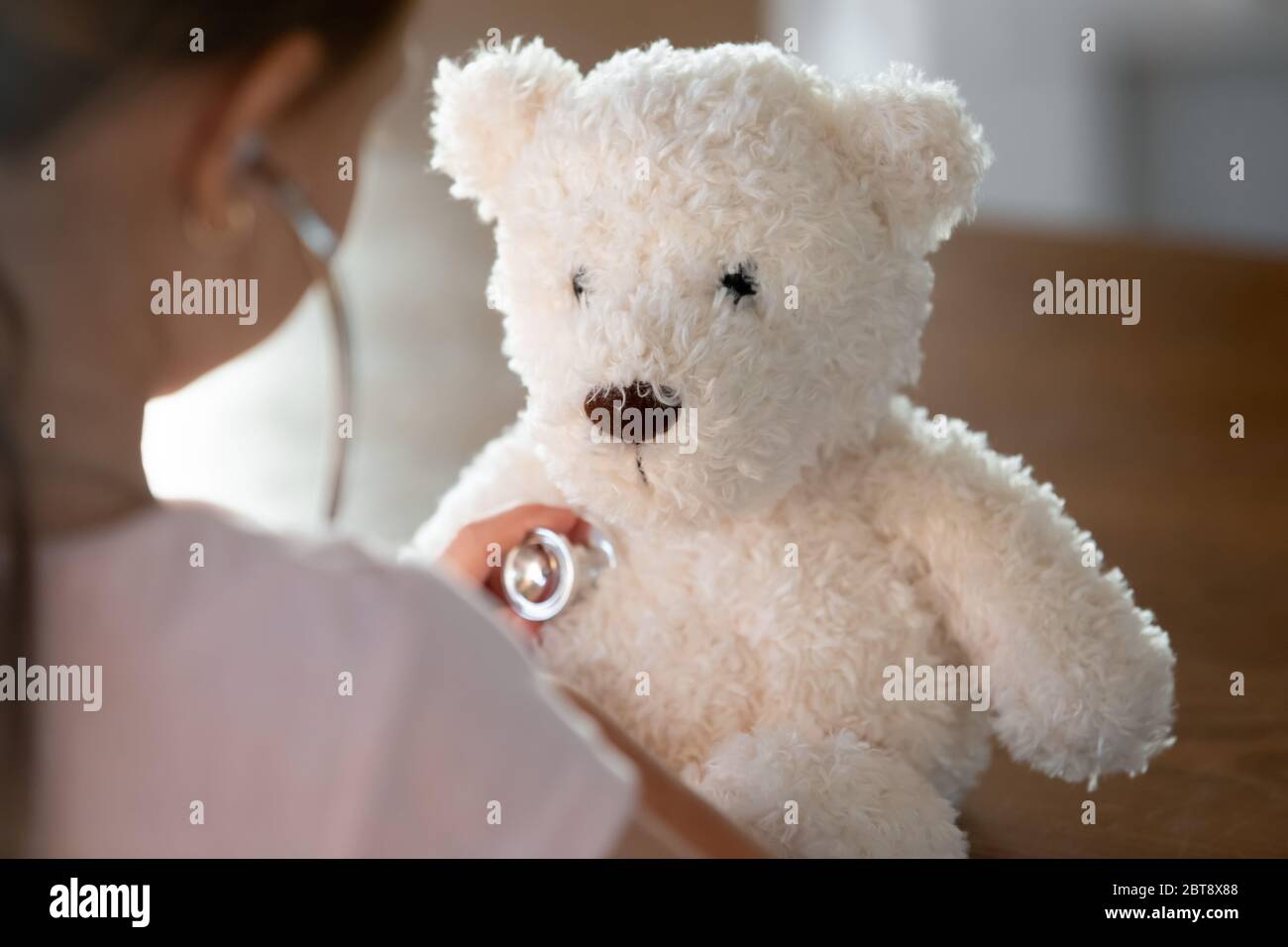 Il bambino attento esamina l'orso peluche del teddy Foto Stock