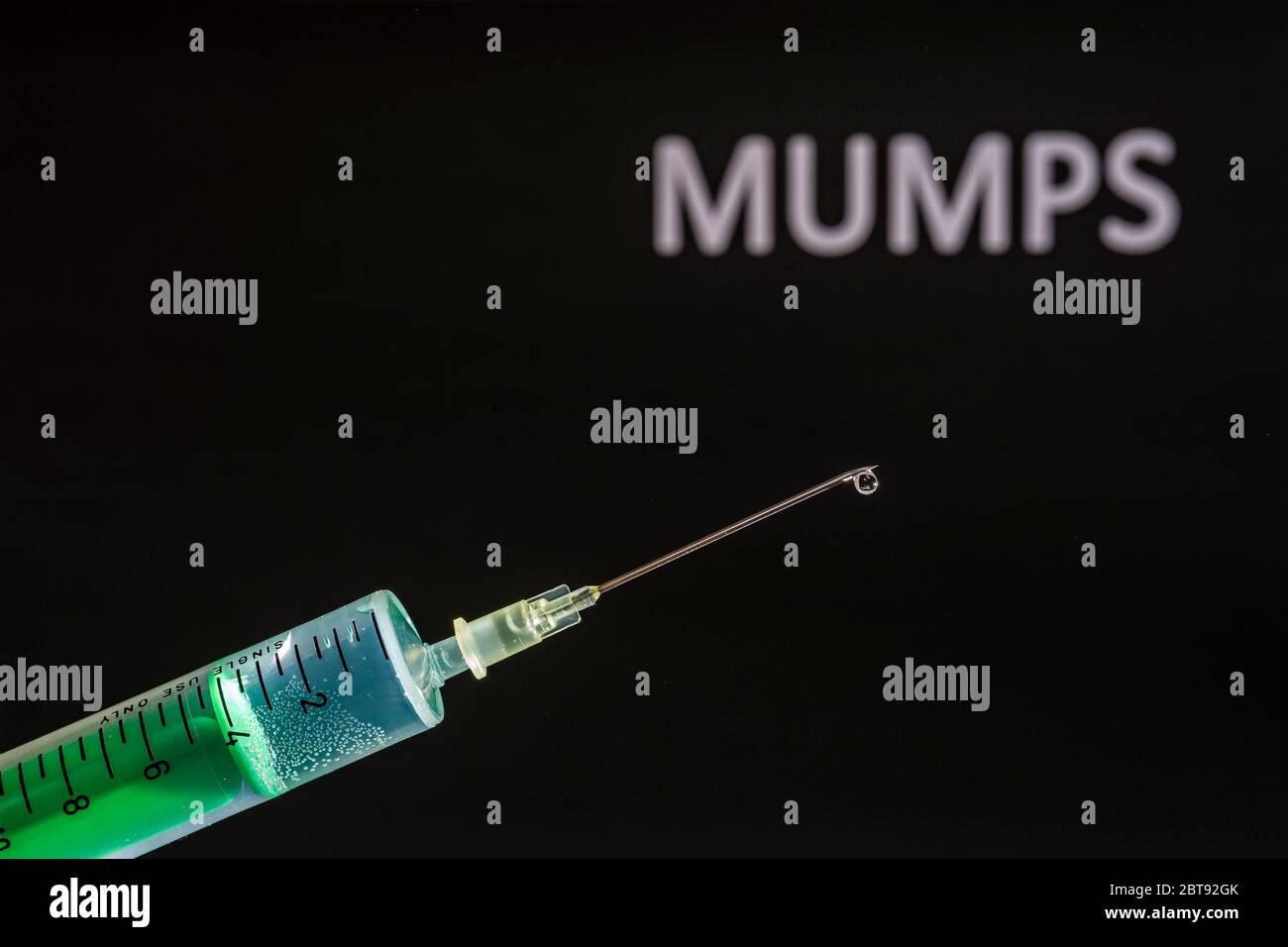 Questa figura mostra una siringa monouso con ago ipodermico, MUMPS scritto su una scheda nera dietro Foto Stock